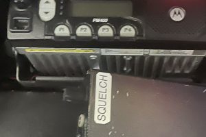 IMG_4466 – Sage Auto Sport Close-up of a Motorola car radio control panel showing a small display, four function buttons labeled F1–F4, and an up/down rocker on the left; a red strap is partially visible in the background.
