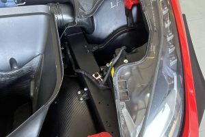 IMG_4477 – Sage Auto Sport Open rear trunk area of a red sports car, showing a black LF-labeled panel, red frame parts, and exposed wiring near the taillight.