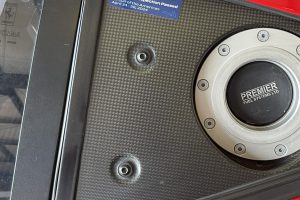 IMG_4480 – Sage Auto Sport Close-up of a red car panel with a blue 'Technical Inspection Passed' sticker for Ferrari Challenge, showing the fuel cap and carbon-fiber texture nearby.