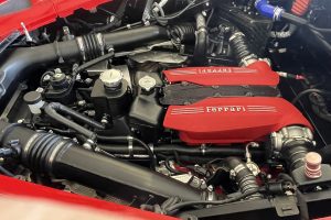 IMG_4482 – Sage Auto Sport Engine bay of a red Ferrari, with a bright red intake cover reading Ferrari and visible black hoses and components