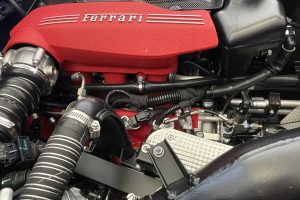 IMG_4483 – Sage Auto Sport Red Ferrari engine intake cover with 'Ferrari' logo and surrounding hoses and components in the engine bay