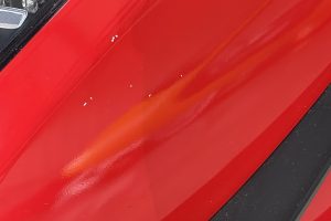 IMG_4490 – Sage Auto Sport Close-up of a glossy red car panel with a small white paint chip near the edge.