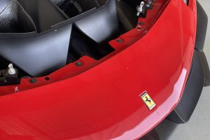 IMG_4491 – Sage Auto Sport Close-up of a red Ferrari front with badge visible and part of wheel and black bumper details.