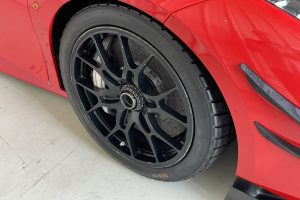 IMG_4493 – Sage Auto Sport Close-up of a red sports car wheel: black multi-spoke rim and low-profile tire in the wheel arch area